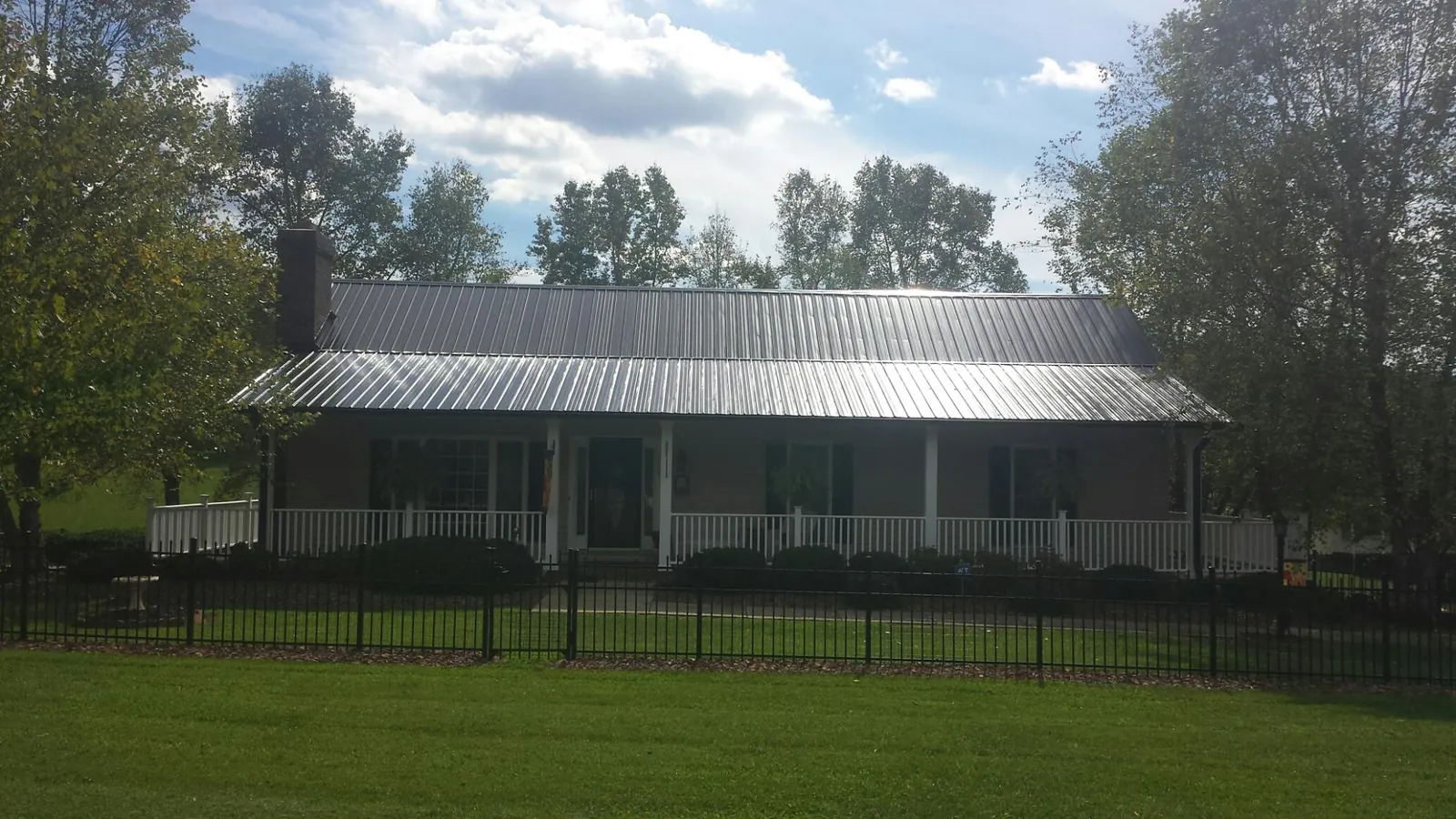Gray metal roof on a brick ranch with a full width front porch — Gutter Guard Installation work by our crew in Middleport