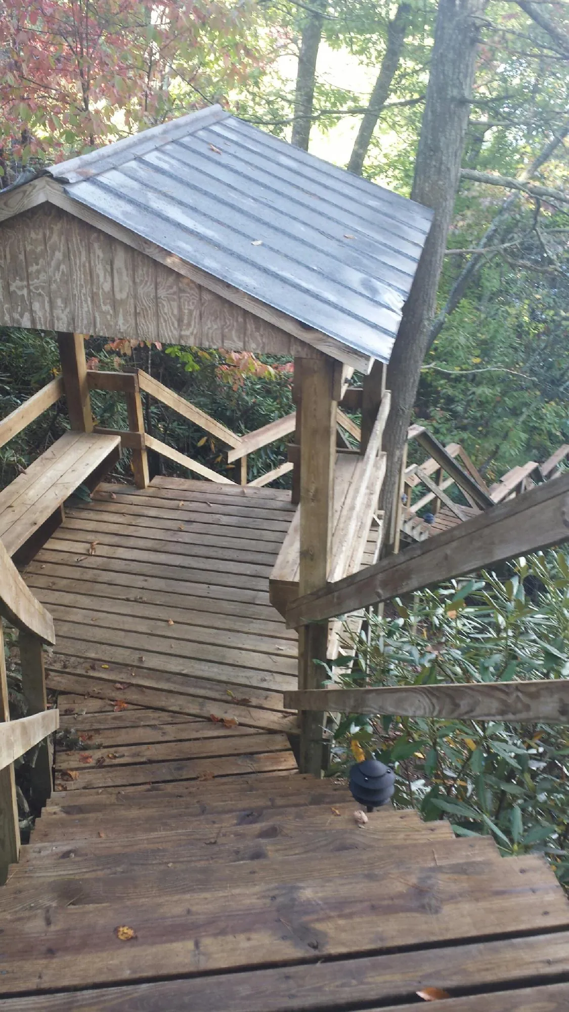 Metal roofed shelter over wooden steps on a wooded walkway — Skylight Repair & Installation work by our crew in Middleport