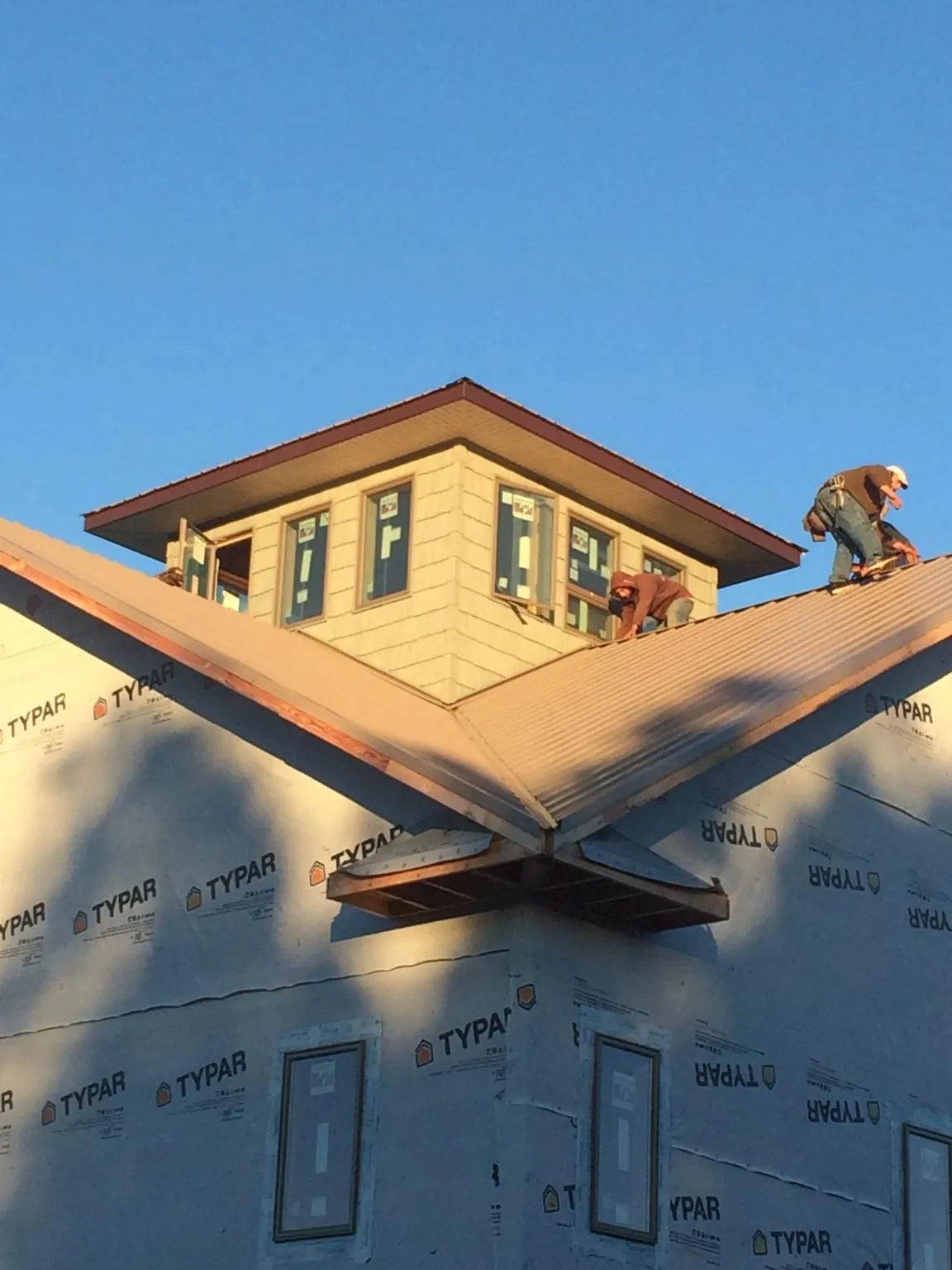 Roofers working around a rooftop cupola on a new metal roof at sunset — Roof Waterproofing in Middleport by Roofing Brothers